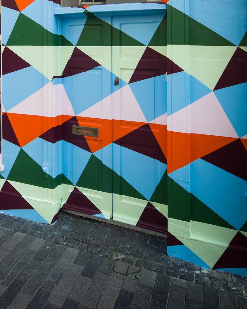 The shopfront at 35 Ashe St painted in a geometric mural of blue, orange, green and maroon triangles
